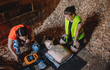 Dvě ženy nasazují AED na recusitační figurínu